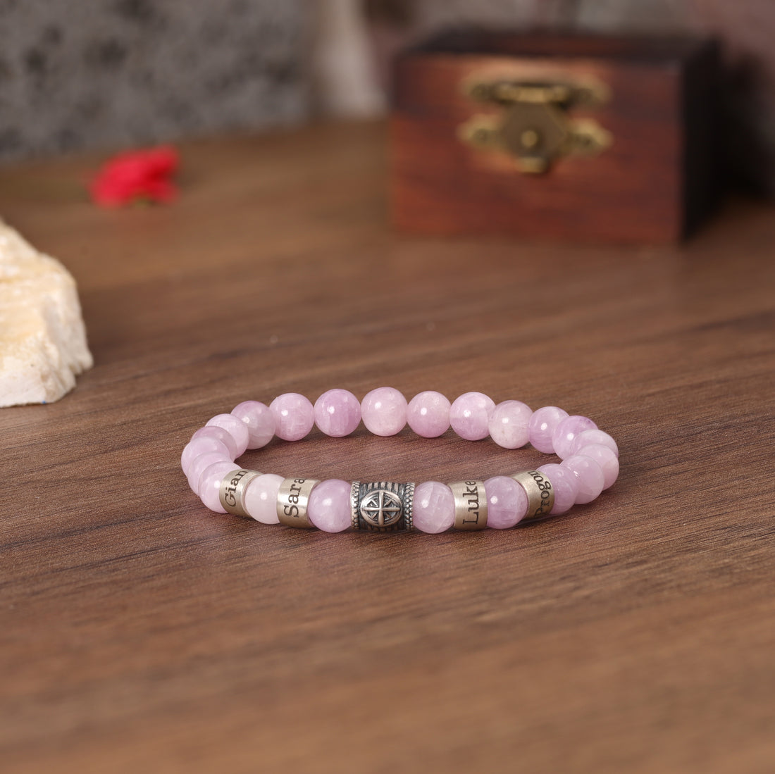 Pink quartz bracelet featuring a Compass charm, personalized with loved ones' names.
