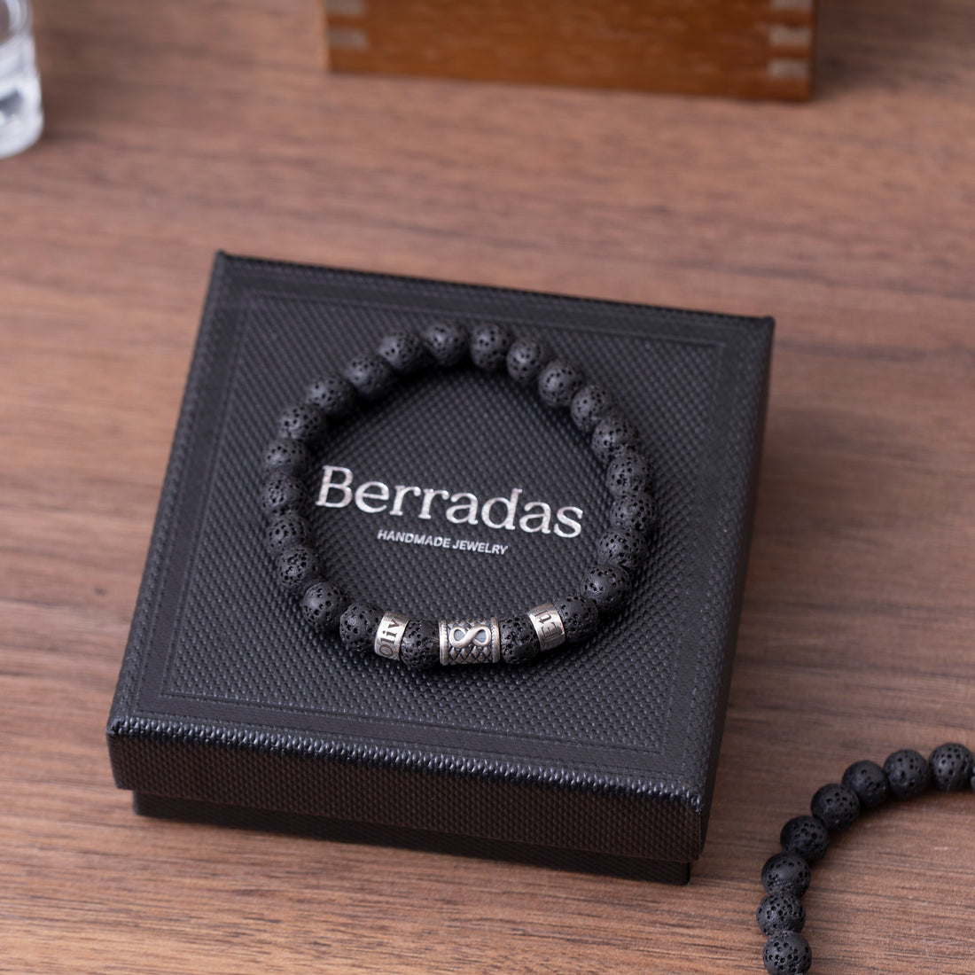 Elegant men's bracelet featuring black lava beads, a shiny infinity symbol, and a space for a custom name engraving, ideal for a romantic Valentine's gift for a boyfriend.